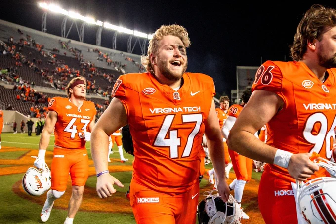 Griffin Armstrong walks on the football field with teammates in orange jerseys