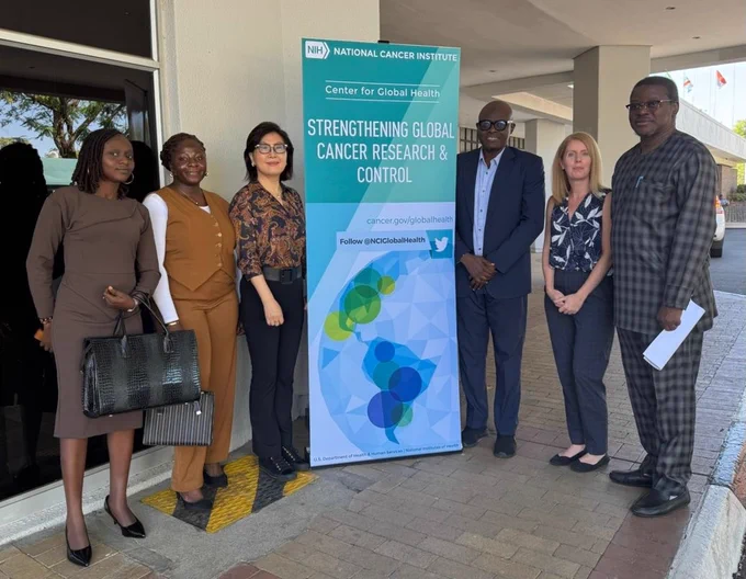 Members of the Center for Global Oncology pose next to a conference sign in Botswana