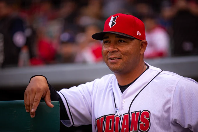 Former Indianapolis Indians manager Miguel Perez stands with his arm propped up on the dugout wall.