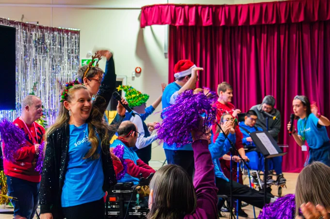 People dancing and waving colourful material.