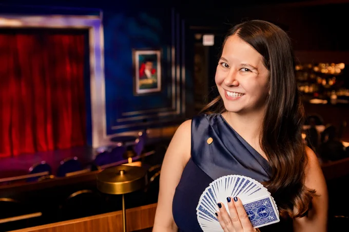Tori Noquez fans a deck of cards and smiles at the camera.