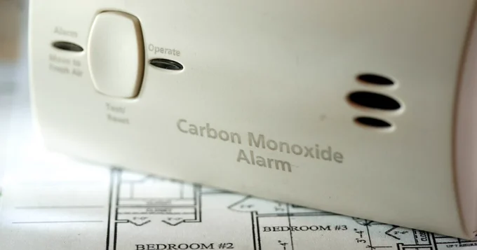 Close-up of a carbon monoxide alarm placed on architectural plans.