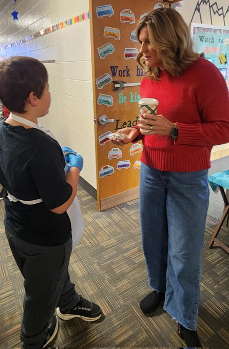 Students delivering hot chocolate and a treat to staff. 