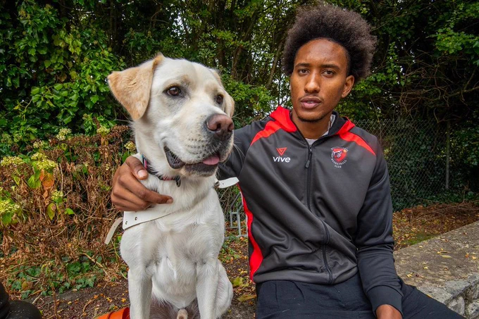 Dog in Training Nelson and Josh Tomaic of Ballincollig Basketball team sitting on a wall facing towards the camera.