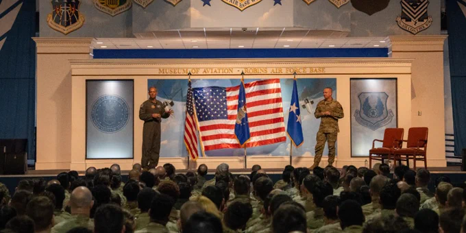 Two Airmen speak on a stage.