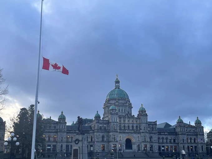 A photo of the British Columbia Parliaments Buildings with the Canadian flag flying at half-mast.