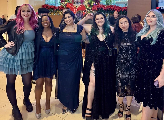 A group photo of a bunch of lovely smart cool women all dressed in formal attire and smiling at the camera. 