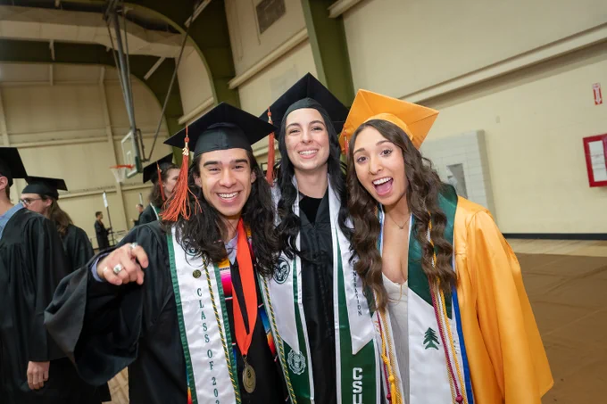 Three C S U graduates smile for a group photo before their commencement ceremony. 
