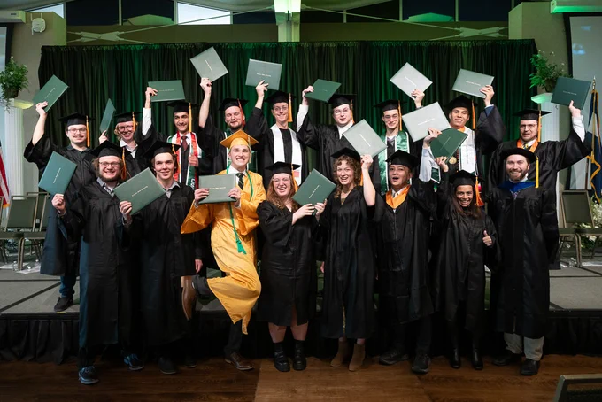 A group photo of C S U graduates holding their diplomas at their commencement ceremony.