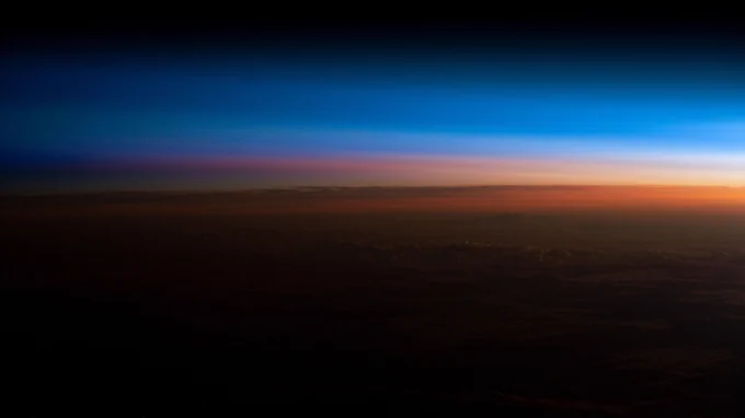 An orbital sunrise begins illuminating Earth's atmosphere and revealing the cloud tops in this photograph from the International Space Station as it orbited 260 miles above southern Brazil.
