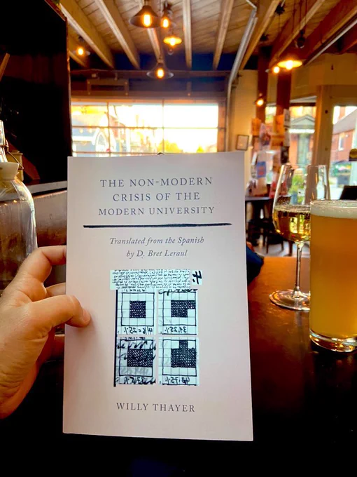 Hand holding Non-Modern Crisis of the Modern University with a beer and a wine