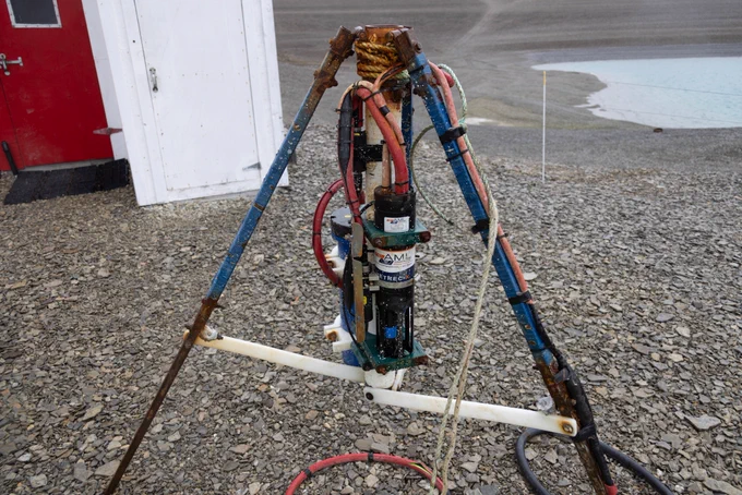 A rusty cylindrical object supported by a tripod.