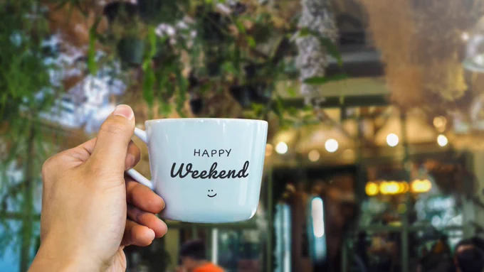 A hand holding a mug with the words happy weekend on it