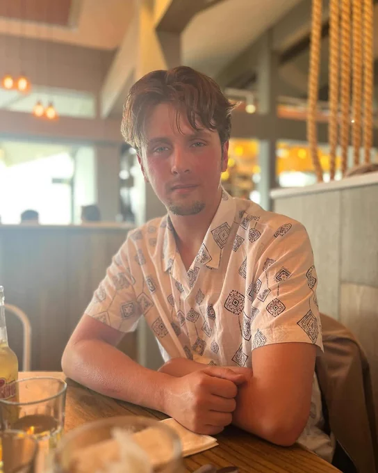 Marshall sitting at a table in a restaurant, wearing a patterned short-sleeve shirt.