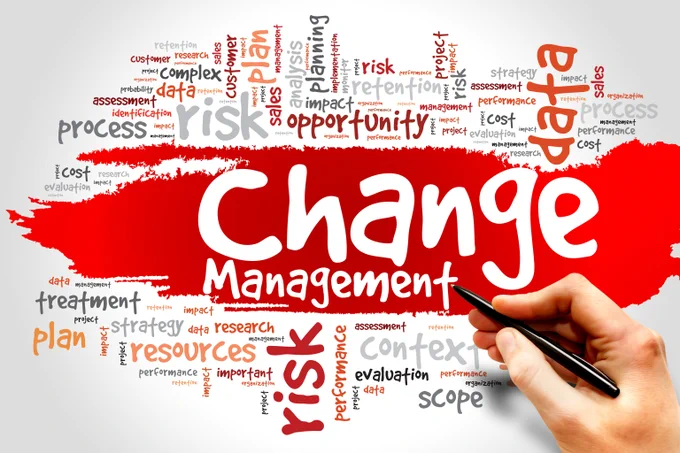 White page with a red splash of color and the word "change management" in white with a person's hand holding a black pen. The words "process" and "risk" and "opportunity" are also on the page with many other words including "data" and "cost."