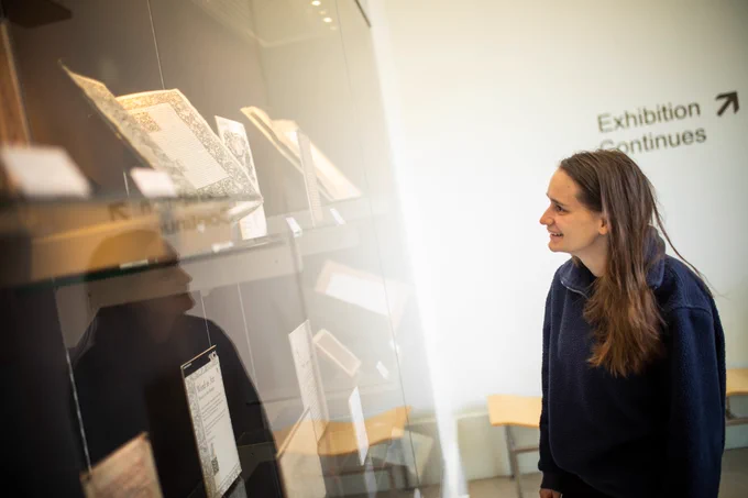 A person looking at text panels in a display case.