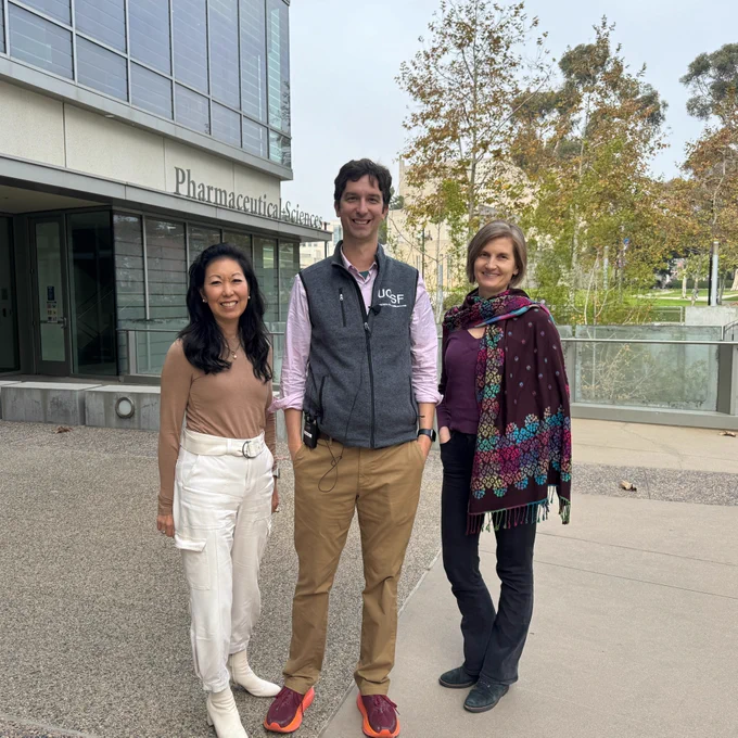 Three smiling scientists standing in front of a building