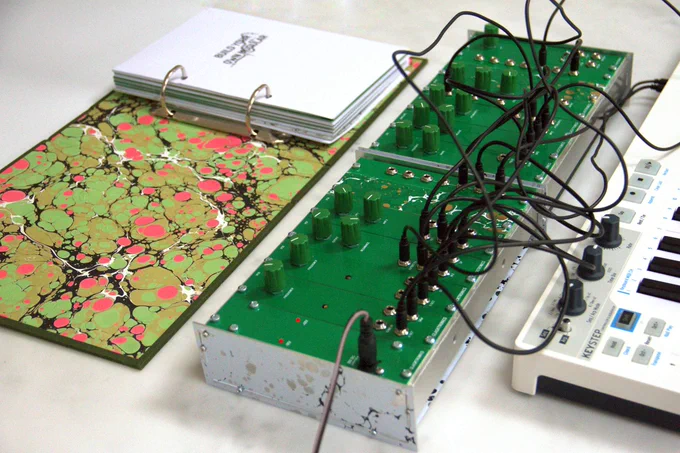 Assembled system with open book, enclosure and modules with green knobs and wires, keyboard.