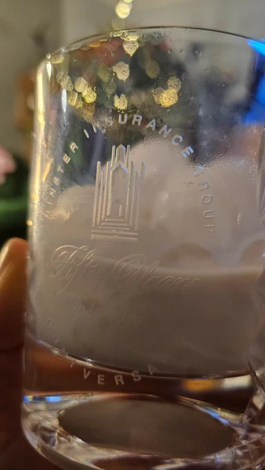 A crystal straight-sided tumbler, engraved with "Minster Insurance Group. Fifty Years. 1940-1990. Anniversary" There's also an engraved picture of a Minster in the middle.