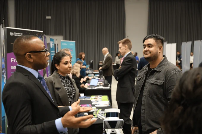 A man listens to two exhibitioners as they explain how their mechanical device works at Venturefest West Midlands 2024