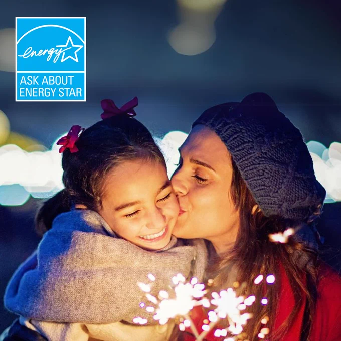Mom kisses daughter on the cheek while they look at lit sparklers in their hands