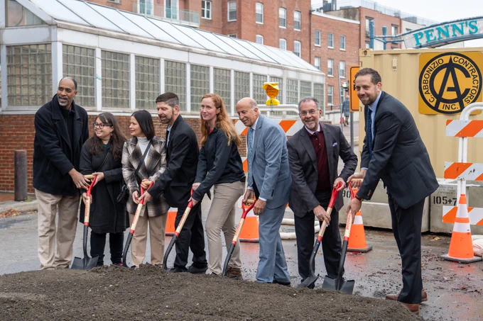 Speakers pose for a photo with shovels and dirt.