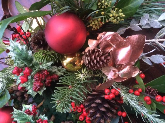 A picture of festive green and red foliage with red and gold baubles