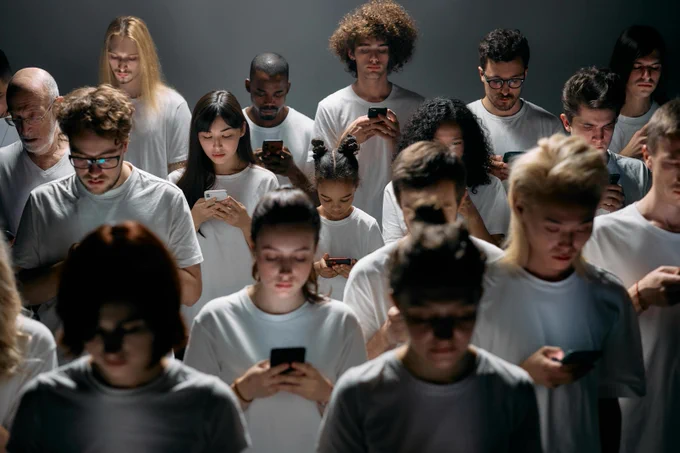 Lots of people standing in rows using their phones, not interacting