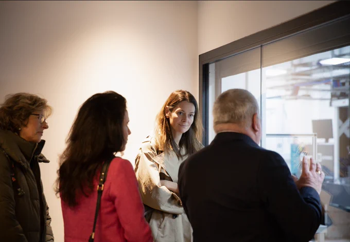 Minister of State Poppy Gustafsson stands in a group listening to CLF director John Collier as she views EPAC through a window