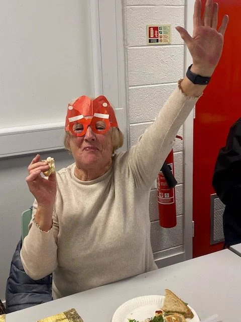 A lady in a party hat eating and waving