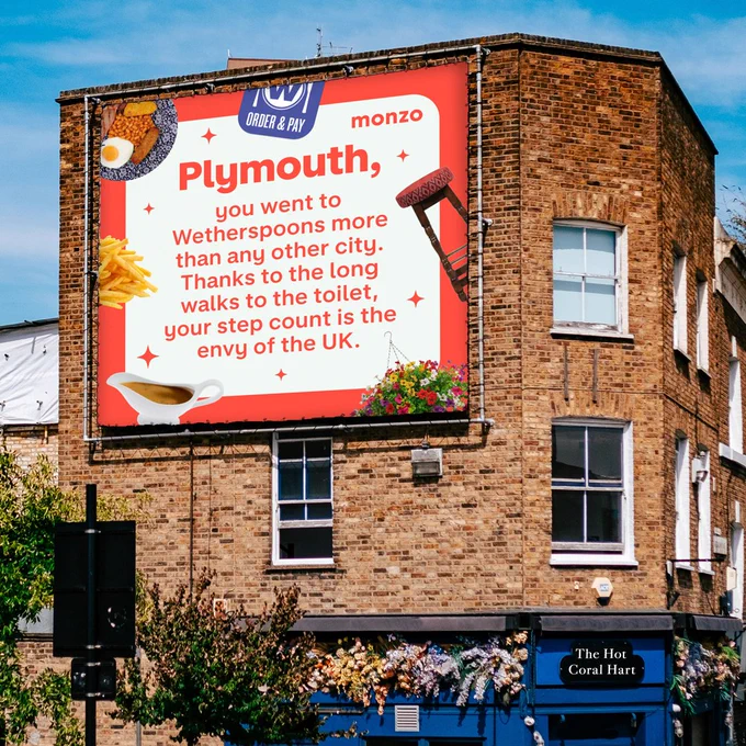 A billboard on a side of a house that reads: 'Plymouth, you went to Wetherspoons more than any other city. Thanks to the long walks to the toilet, your step count is the envy of the UK.' Surrounded by chips, a bar stool and an English breakfast.