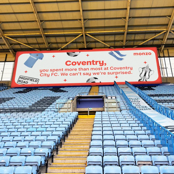 A billboard in Coventry Football Stadium reading: 'Coventry, you spent more than most at Coventry City FC. We can’t say we’re surprised.' Surrounded by images of the Coventry FC kit and the FA cup trophy.