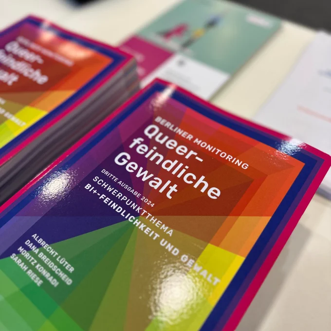 Zwei Stapel ausgedruckter Exemplare des Berichts "Berliner Monitoring Queerfeindliche Gewalt" liegen auf dem Tisch.