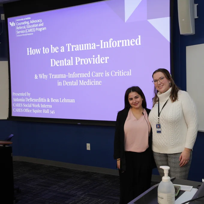 Antonia DeBenedittis and Bess Lehman in front of their title slide, which reads: "How to be a Trauma-Informed Dental Provider and Why Trauma-Informed Care is Critical in Dental Medicine."