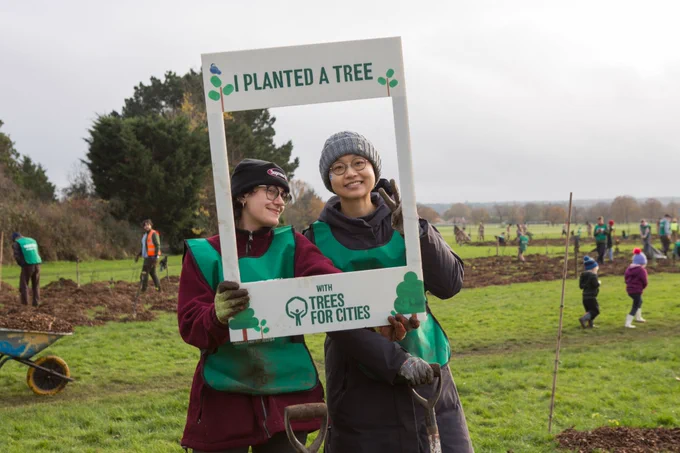 Two Trees for Cities volunteers pose with a photo prop at a planting event