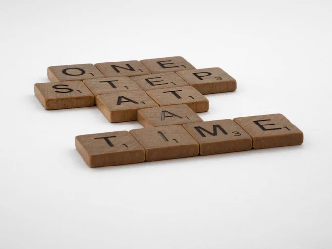 Scrabble tiles showing "One Step At A Time"