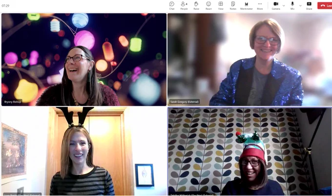A photo of four women on a Teams online meeting in Christmas outfits smiling. 