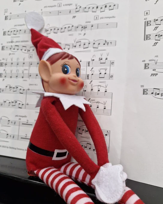A toy elf sat in front of some music 