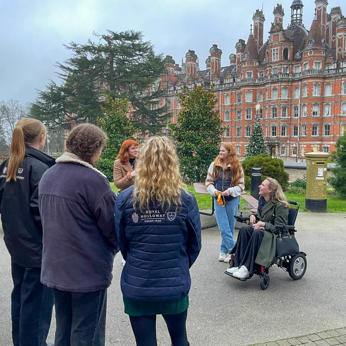 Sophie Christiansen CBE in front of Founder's Building and gold postbox, students gather around