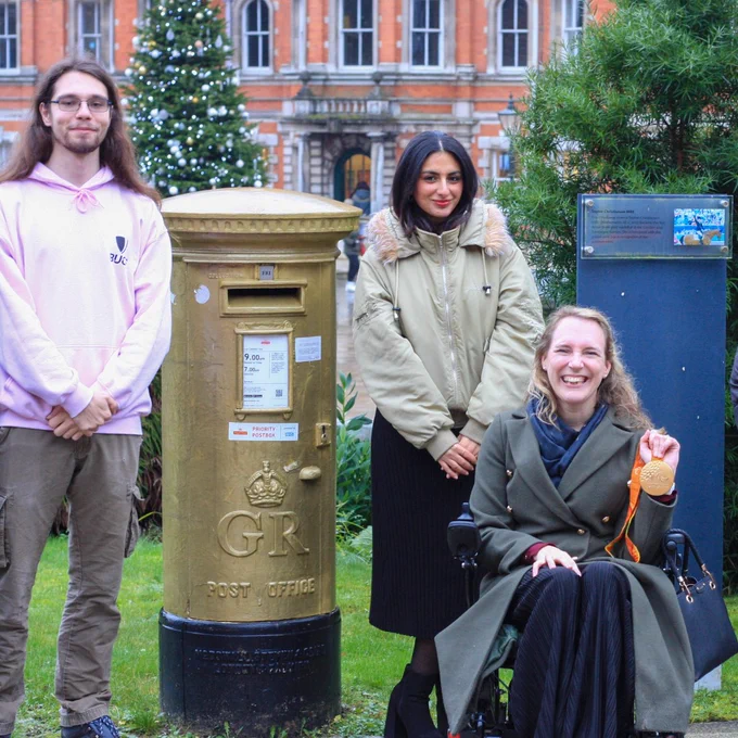 Sophie Christiansen CBE with two students in front of gold post box