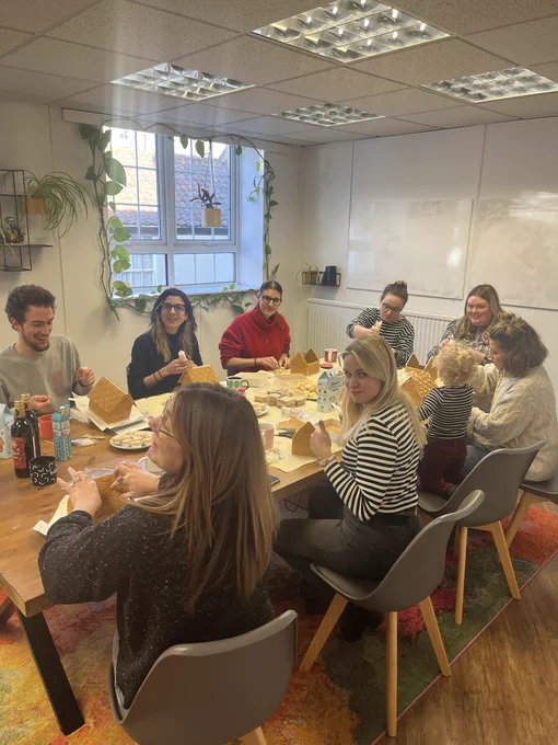 The Candour team at the table making gingerbread houses looking suitably happy