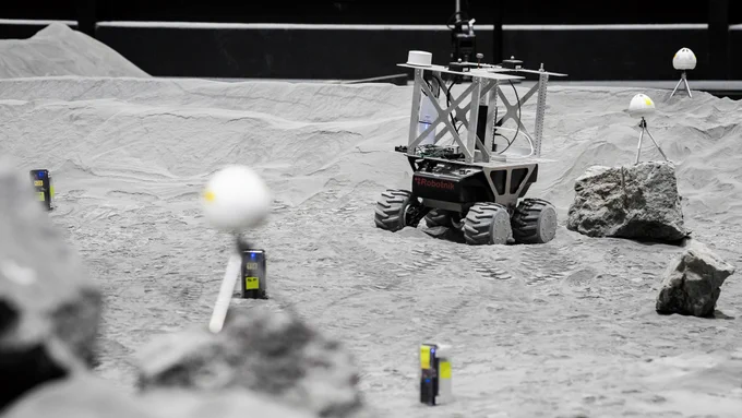 Ein Rover fährt zwischen Sensoren und Steinen in der LUNA-Halle. Die Steine sind der Mond-Geologie nachempfunden.