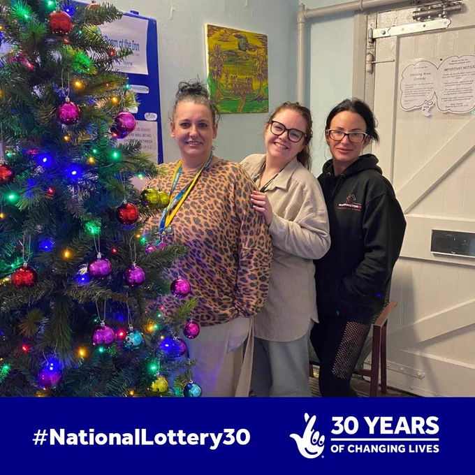 Three people standing beside a Christmas tree