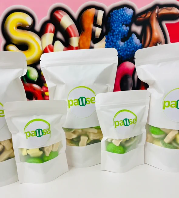 Photo shows white bags of sweets with the Pause logo on them. The sweets are green and white, like the logo. 