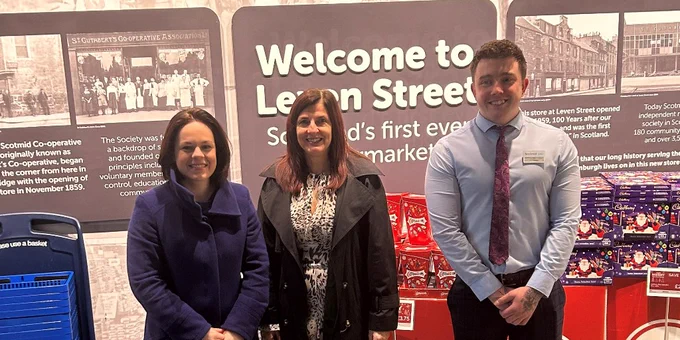 Deputy First Minister Kate Forbes standing with two employees of Scotmid. A sign in the background reads: "Welcome to Leven Street: Scotland's first ever supermarket."