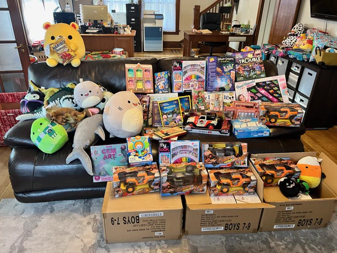 Collection of toys laid out on a black sofa and on the floor of a room.