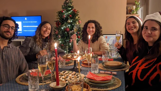 CDT Europe's team around a dinner table with food, drinks and candles, and a Christmas tree in the background