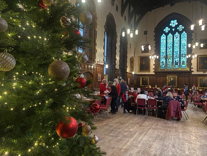 View of the Christmas Tree in Durham Castle Great Hall, with numerous visitors in the background. 
