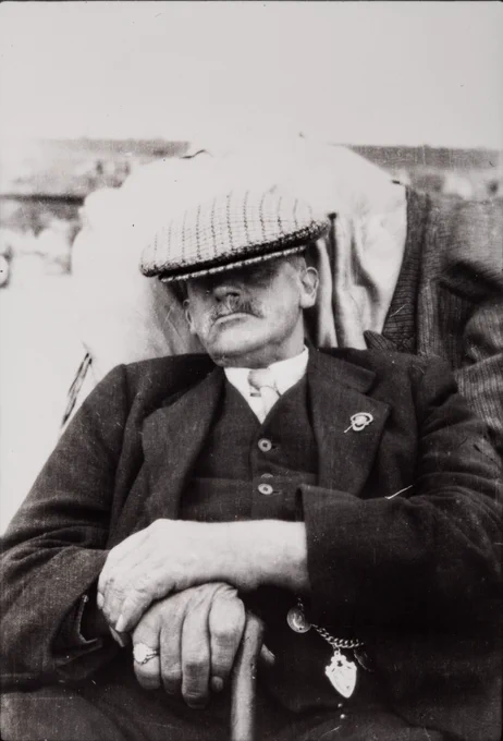  A smartly dressed older gentleman taking a nap, with his flat cap covering his eyes. The photograph was taken in the 1940s or 1950s by Jack Hulme.