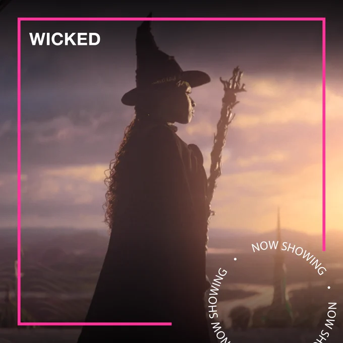 A woman dressed as a witch looks out at the city. Text - Wicked, Now Showing